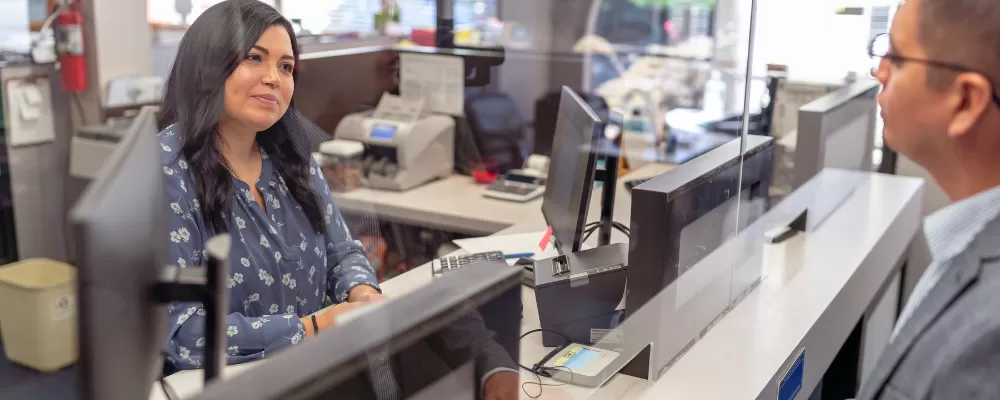Benefits of Joining A Credit Union - Woman handing cash to a financial representative at a credit union
